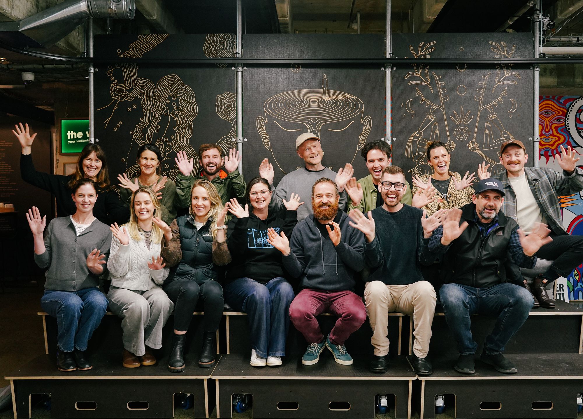 The Rewiring Aotearoa team sitting together, all waving with their hands up